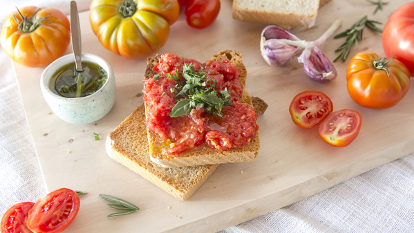 KI generiert: Toast mit Tomatenpaste, Kräutern und Knoblauch auf Holzbrett, umgeben von frischen Tomaten und Olivenöl.