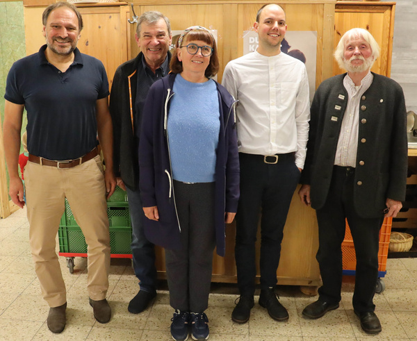 KI generiert: Fünf Personen stehen nebeneinander vor einem Holzschrank. Text: "DIE KO".