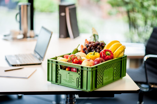Mann übergibt Kiste mit Obst & Gemüse