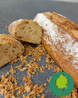 KI generiert: Ein Laib knuspriges Baguette, halbiert, mit knusprigen Zwiebeln auf dunkler Fläche.