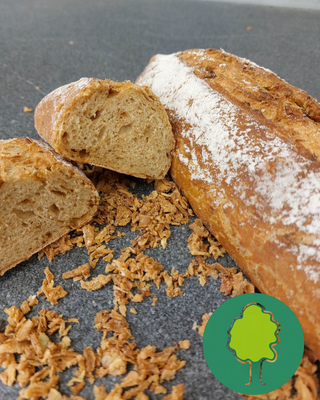 KI generiert: Ein Laib knuspriges Baguette, halbiert, mit knusprigen Zwiebeln auf dunkler Fläche.