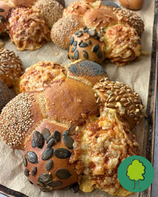 KI generiert: Frische Brötchensorten mit verschiedenen Saaten auf einem Backblech.